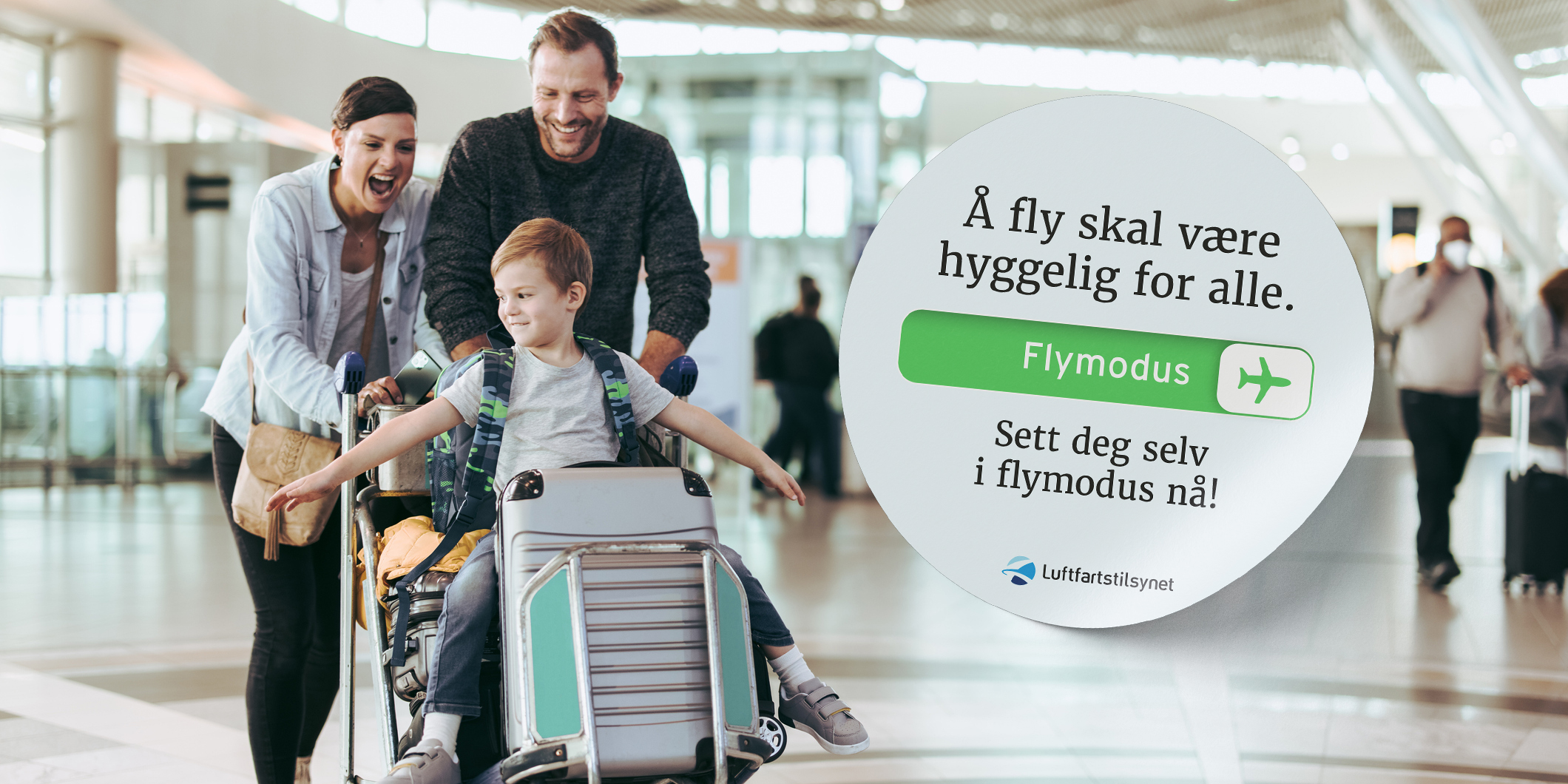 A joyful family shares a moment of happiness at the airport, with their son seated on the luggage beaming a wide smile. In the background, a campaign by the Norwegian Civil Aviation Authority encourages setting electronic devices to airplane mode for a pleasant flying experience for everyone.